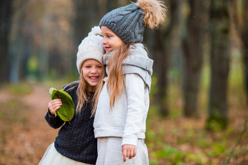 two adorable girls in forest at warm sunny autumn day