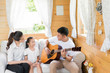 © torwaiphoto - Dad playing guitar for a family. And singing happily in the hous