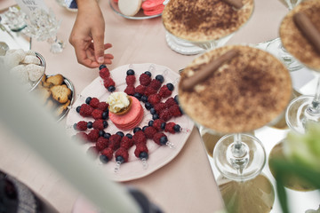 Woman takes a stick with berries from the plate