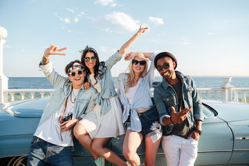 Sticker - Cheerful young friends standing outdoors and showing peace sign