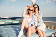 © Drobot Dean - Two gorgeous young women sitting on car