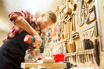 Wall Mural - carpenter with drill drilling plank at workshop