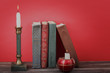 Art concept. Vintage books, burning candles in candlesticks on red background