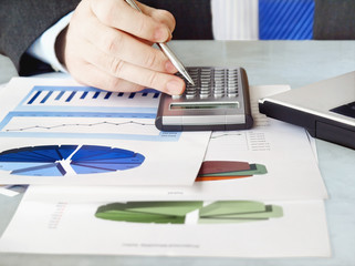 Fototapete - Closeup of male hand with pen using calculator on financial  charts 