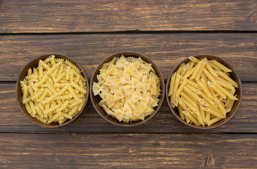 Raw pasta in wooden bowls