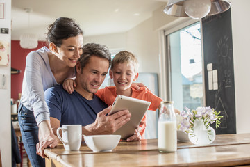 A family using a tablet while having breakfast in the kitchen