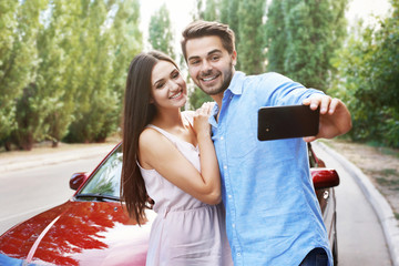 Poster - Beautiful young couple taking selfie near car