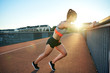 Female jogger stretches against bridge railing