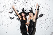 Two happy women in black witch halloween costumes on party