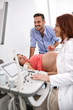 © didesign - Happy couple looking at ultrasound results with doctor