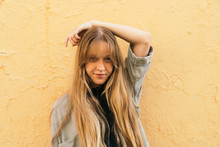 Pretty Young Girl With Long Blonde Hair On Yellow Textured Wall