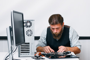 Poster - Bearded engineer assembling computer at workplace. Repairman fixing computer inside circuit in office. Electronic renovation, technology, business concept