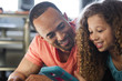 © Cavan Images - Close-up of father and daughter playing video game while lying at home