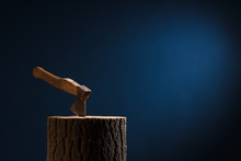 The Axe Stuck In The Wooden Stump On A Dark Background.