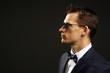 © petrdlouhy - Profile of young businessman in suit on gray background with sunglasses, left you can write some text