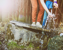 Hipster Young Girl Satisfies Thirst, Substituting Hands Under The Water Pump In The Village In Summer