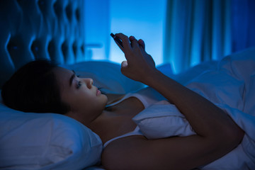 asian women are using the smart phone on the bed before she slee