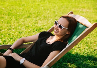 Happy Young Woman Relaxing Outdoor on the Background with Green