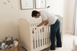 © Gary - HIspanic dad putting newborn baby in crib