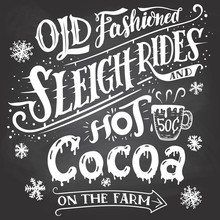 Old Fashioned Sleigh Rides And Hot Cocoa On The Farm. Chalkboard Hand-lettering Sign. Hand Drawn Typography With A Mug Of Hot Cocoa. Signpost On Blackboard Background With Chalk