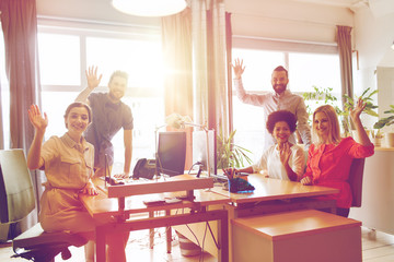 happy creative team waving hands in office