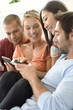 © goodluz - Friends at home playing with smartphones, connecting people