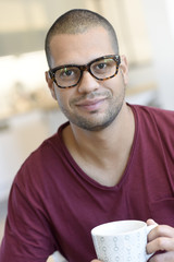 Portrait of hispanic guy with eyeglasses drinking tea