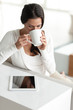 Woman at home with Digital Tablet drinking coffee