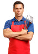 © Eric Hood - Man in red chef's apron with arms crossed clutching cooking utnensils isolated on white background
