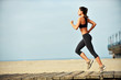 Leinwandbild Motiv Attractive fit young woman running on Santa Monica Beach boardwalk pacific ocean and pier in background