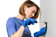© Eric Hood - Female woman do-it-yourself electrician installing light switch on drywall isolated on white background