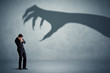 © ra2 studio - Business person afraid of a big monster claw shadow concept