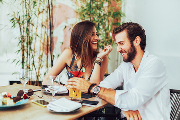 Young couple sitting in the outdoor bar and drink cocktails