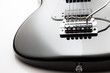 Black electric guitar close up on a white background.