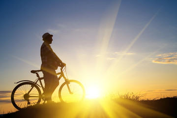 Silhouette of sports person cycling on the field on the beautifu