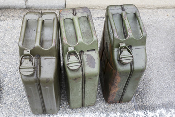 three Old jerry cans with gasoline on the road