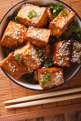 Wall Mural - Fried tofu cheese with sesame and garlic in a bowl close-up. Vertical top view
