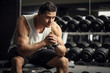 Thoughtful serious sportsman sitting in a gym
