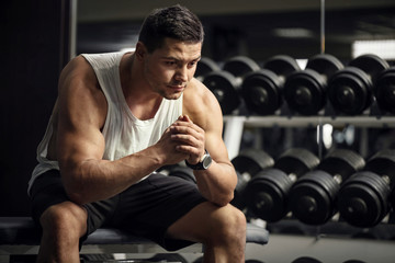 Wall Mural - Thoughtful serious sportsman sitting in a gym