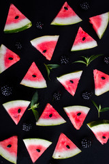 Wall Mural - Triangular pieces of watermelon with seeds. Blackberry and mint. black fone.Top view. Flat lay.