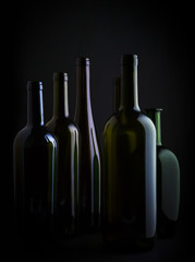 different colorful empty wine bottles family on black background