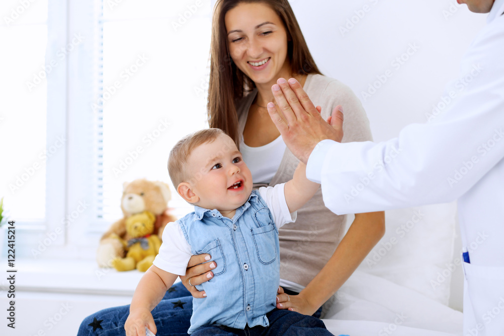 Little boy child  with his mother  at  health exam at doctor's office. Patient  gives five to his physician.