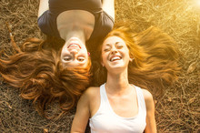 Two Young Girls Having Fun Lying On The Grass.