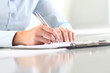 © amedeoemaja - Woman's hands writing on clipboard with a pen; isolated on desk