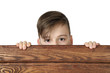 Cute handsome boy peeking from behind wooden fence isolated on white background