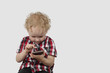 Little boy plays with smartphone on gray background with copy space - Modern gadgets and communication concept - Simplicity and usability