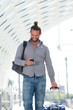 © mimagephotos - Handsome man walking with mobile phone with suitcase