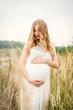 © demchyna - Portrait of a young beautiful pregnant woman with long blond hair in a white dress