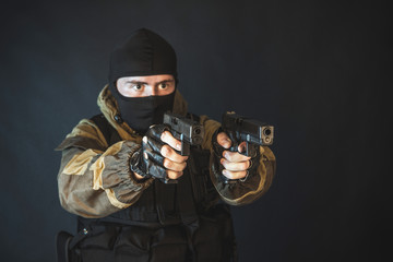 The man in the image of a member of the special forces division with two pistols in blue light. Russian police special force - Special Rapid Response Unit or SOBR (Spetsnaz).