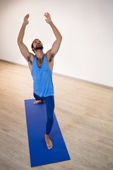 Wall Mural - Man doing warrior pose on exercise mat